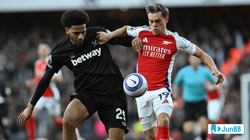 Cầu thủ Arsenal với chiếc áo đỏ đang vượt qua hậu vệ của West Ham trên sân cỏ